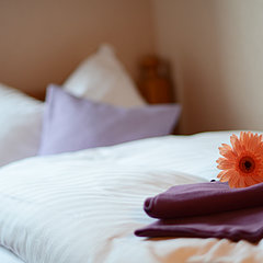 The nicely arranged bed with flower in the hotel room.