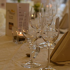 Eine Nahaufnahme eines gedeckten Tisches mit Gläsern, Speisekarten und Blumendekoration.